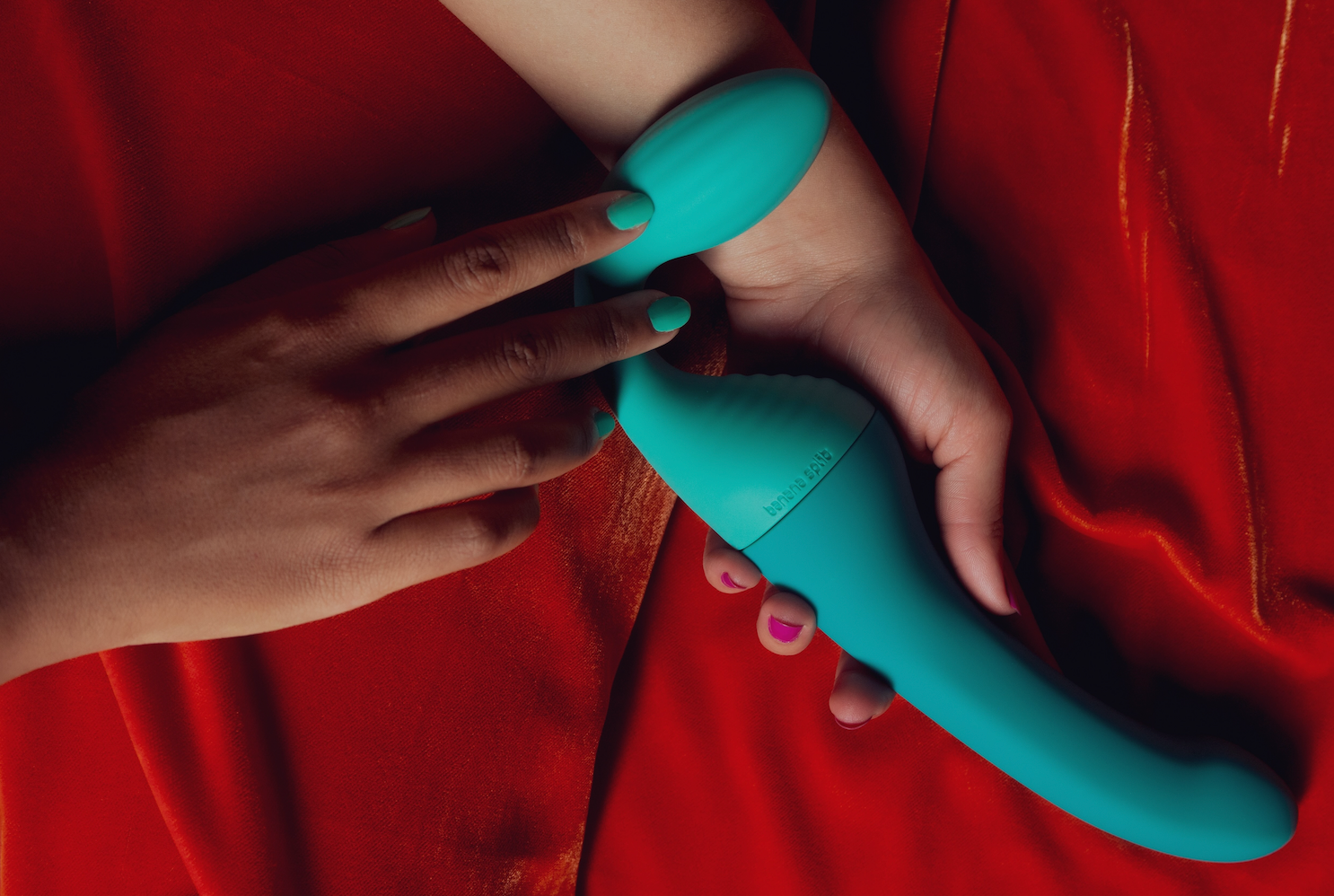 Person holding the Split partner vibrator on a red velvet background