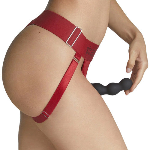 Model wearing the red Strap-on-me Lingerie Harness with a dildo attached to it. 